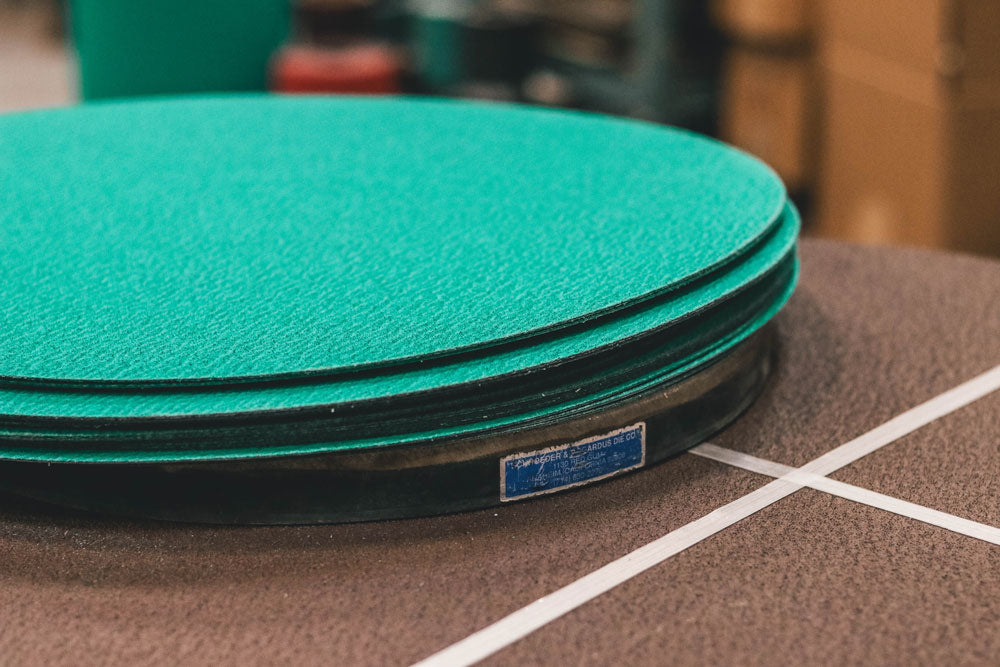 Stack of green sanding discs on a gridded workshop table